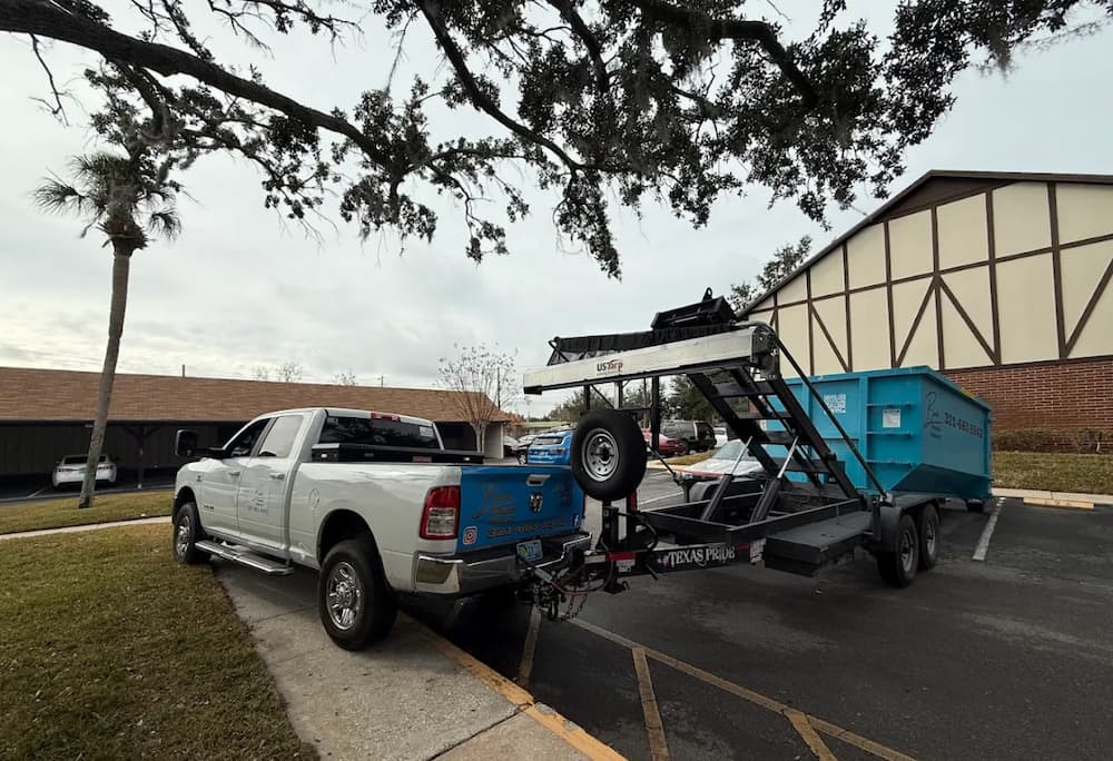 Baus truck and roll-off trailer delivering a teal dumpster in Orlando, FL