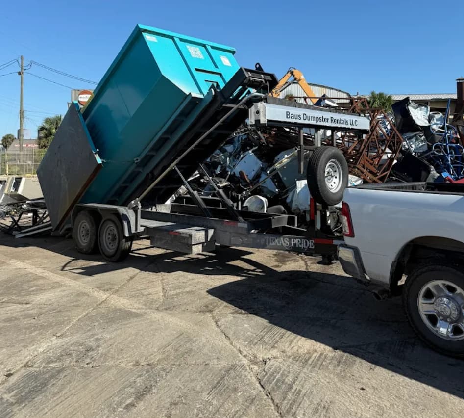 Baus dump trailer tipping a teal roll-off dumpster to unload debris