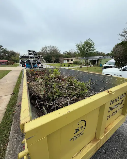 Yellow Baus dumpster loaded with storm and yard debris on an Orlando, FL street