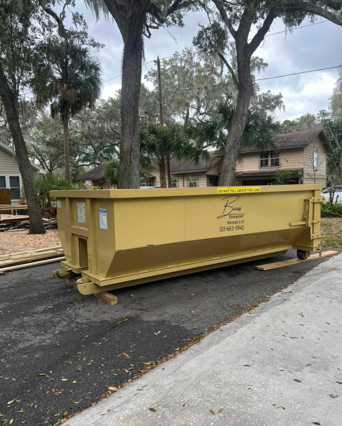 Yellow Baus 15 yard roll-off dumpster under oak trees in Orlando, FL
