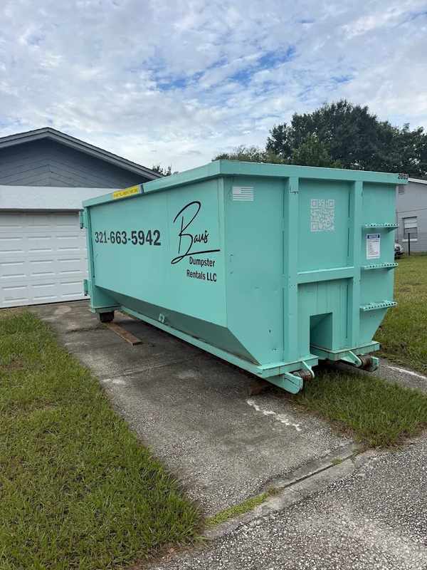 Teal Baus roll-off dumpster in a residential driveway near Orlando, FL