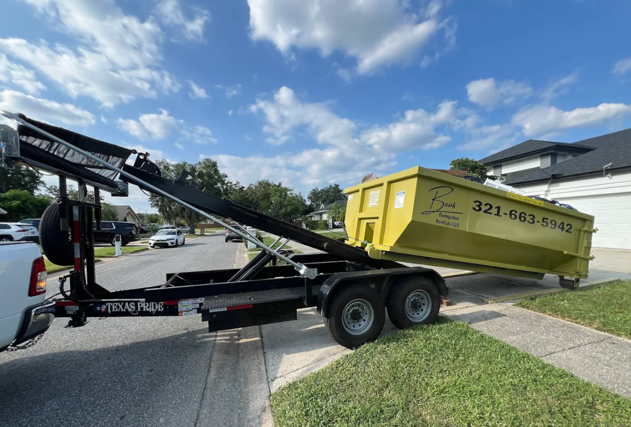 Yellow Baus roll-off dumpster being delivered on a trailer in Winter Park, FL