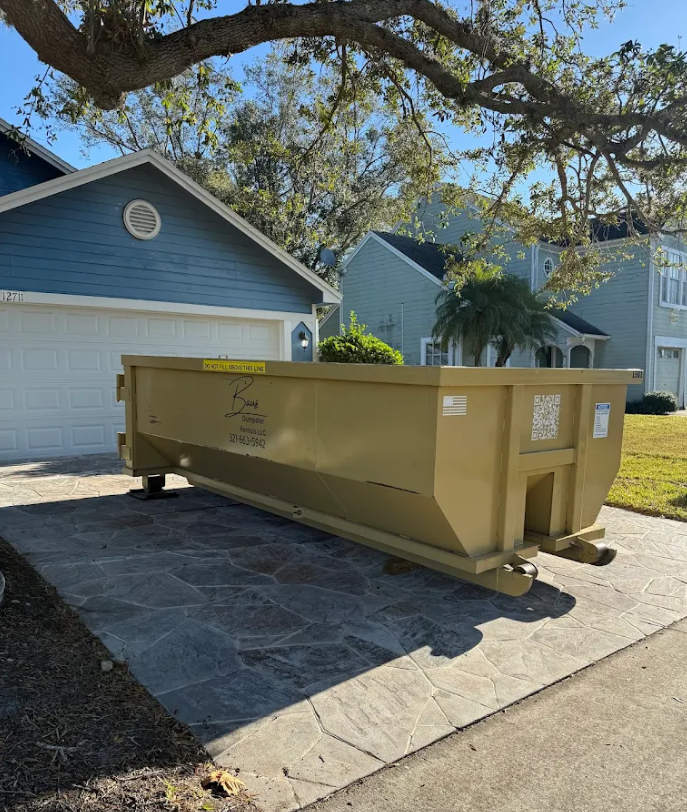 Yellow Baus roll-off dumpster on a driveway in Winter Park, FL
