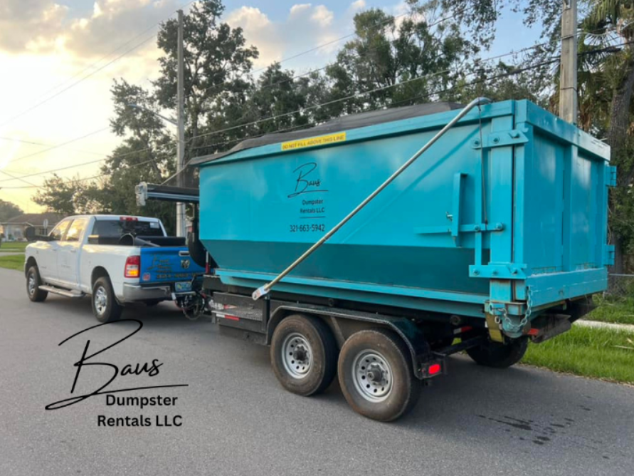 Baus Dumpster Rentals truck towing a teal roll-off dumpster in Lake Nona, FL