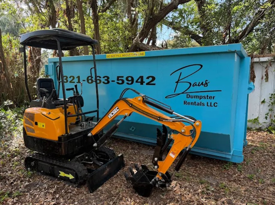 Baus mini excavator parked in front of a teal Baus Dumpster Rentals roll-off dumpster on an Orlando, FL job site
