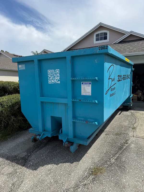 Teal Baus roll-off dumpster in a driveway in Orlando, FL