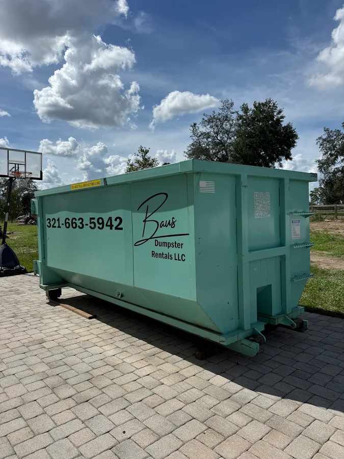 Teal Baus roll-off dumpster on a paver driveway for a large home project near Orlando, FL