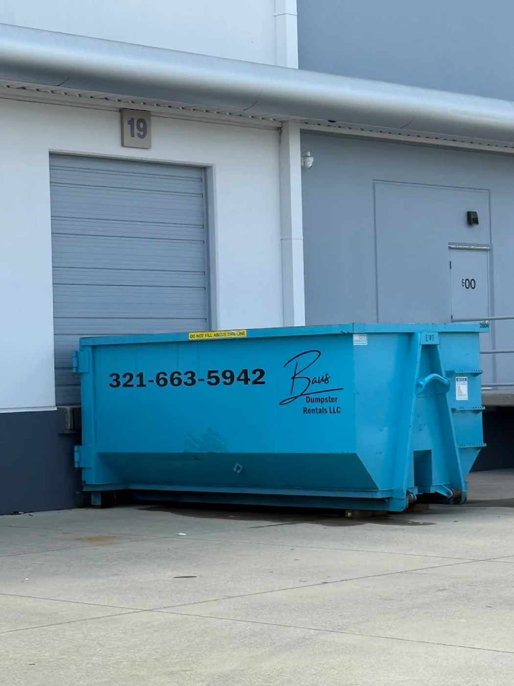 Teal Baus commercial roll-off dumpster at a loading dock in Lake Nona, FL