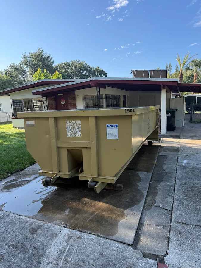 Yellow Baus commercial roll-off dumpster at a building in Orlando, FL