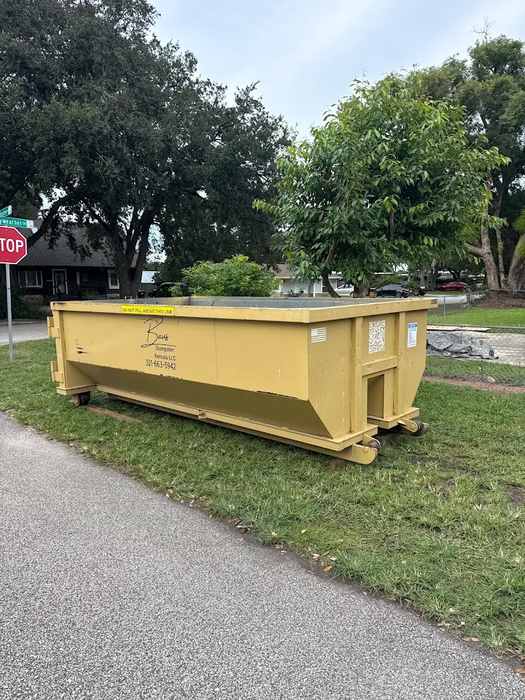 Yellow Baus roll-off dumpster on a lawn in Lake Nona, FL