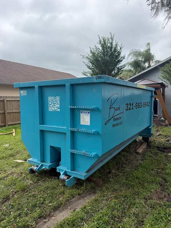 Teal Baus roll-off dumpster in a backyard in Winter Park, FL